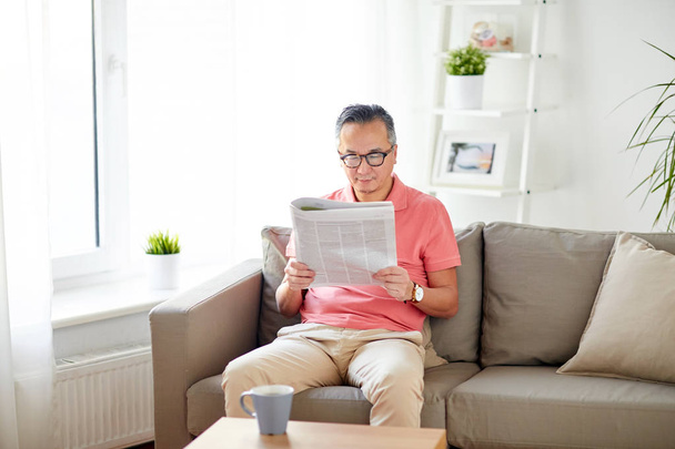 happy man in glasses reading newspaper at home - Zdjęcie, obraz