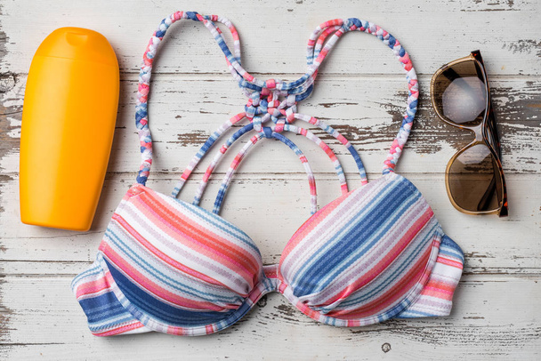 Colorful swimsuit with beach accessories on white wooden table - Fotó, kép