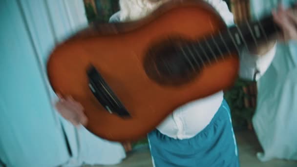Homem alegre vestido de anão barbudo dançando com guitarra acústica nas mãos
 - Filmagem, Vídeo