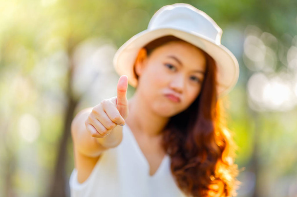 Asian kobieta pokazując kciuki up z naciskiem na rękę na parking tło  - Zdjęcie, obraz