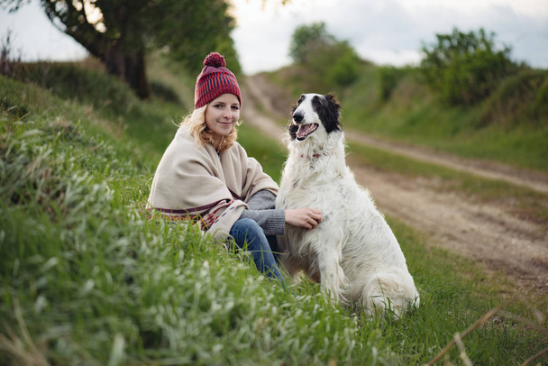 Cute blonde woman with her dog playing outdoors - Photo, Image