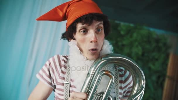 Joyful man in dwarf costume holds broken tin tuba under hand dancing around - Footage, Video