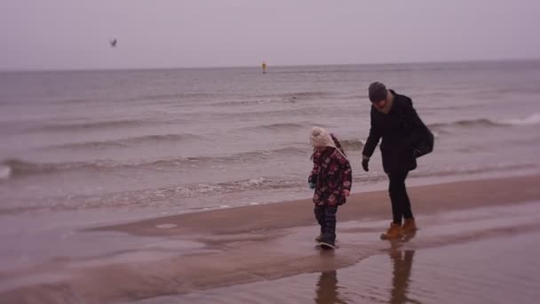 Matka naśladuje dziecko idzie dla córki na ruchomych piaskach, ferie zimowe na morzu - Materiał filmowy, wideo