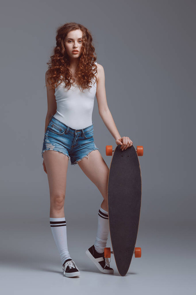Stylish young woman with skateboard  - Foto, afbeelding