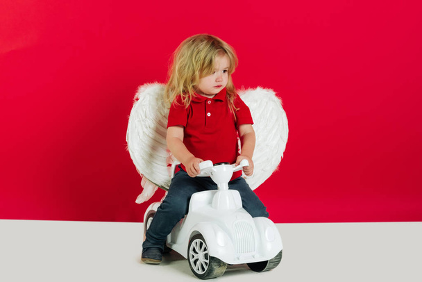 angel boy for valentine greeting, beautiful cupid on car toy - Fotó, kép