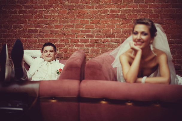 Happy newlyweds rest on the red couches - Foto, immagini