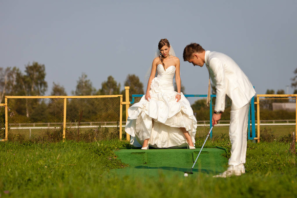 Bride raises her dress standing on the golf field in the front o - Foto, imagen