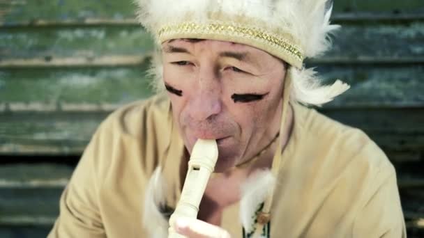 An Indian in a national costume plays a flute near a boat on the river bank 4k - Footage, Video