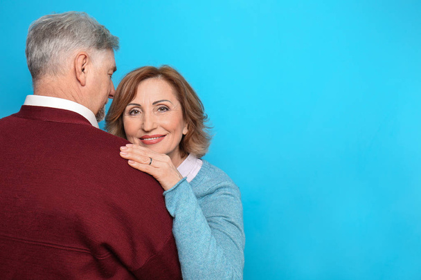Happy senior woman embracing her husband on color background - 写真・画像