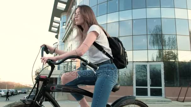 Beautiful woman rides a bicycle near a tall building 4k - Video