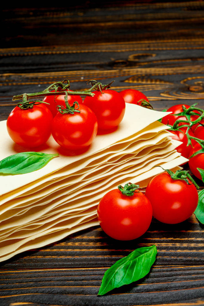 dried uncooked lasagna pasta sheets and tomato - Фото, изображение