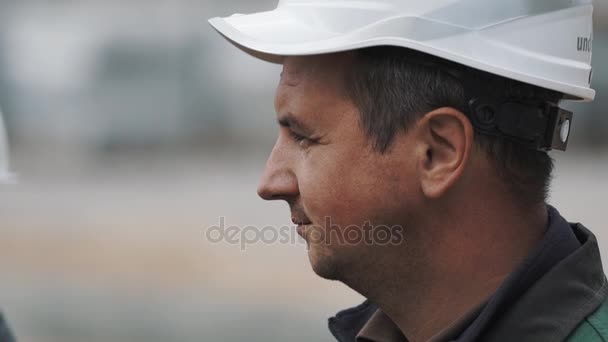 Slowmotion profile portret men in white hard hat at building site focus pull - Imágenes, Vídeo