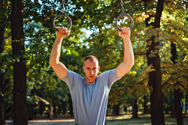 Tough man holding on gymnastics rings - Foto, Bild