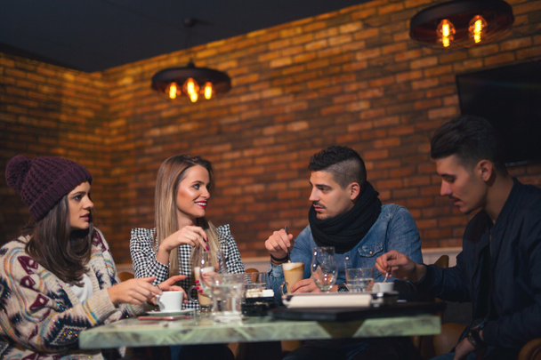 Gruppe junger Leute sitzt in einem Café und amüsiert sich - Foto, Bild