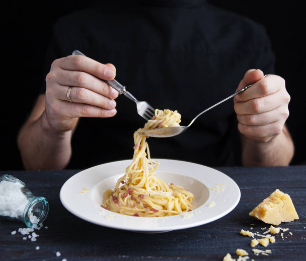 A man eats a fork with Italian homemade pasta spaghetti Carbonara - Fotoğraf, Görsel