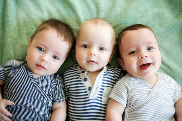Retrato de trigêmeos recém-nascidos estão deitados na cama
 - Foto, Imagem