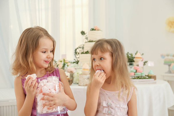 Cute little girls eating tasty sweets at party - Fotó, kép