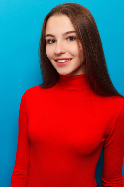 Beauty fashion portrait. Smiling young woman on blue wall background. - Foto, afbeelding