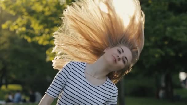 Teenager girl tossing hair in a park - Кадры, видео