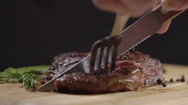 Slow motion. Juicy, fresh, appetizing beef steak cut with a knife, holding the fork. Close-up. Grilled sliced beef steak on cutting board. - Séquence, vidéo