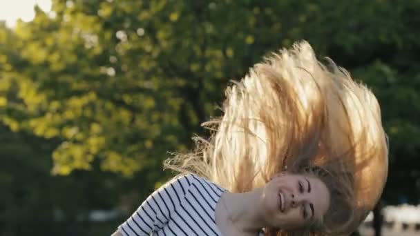 Teenager girl tossing hair in a park - Filmati, video