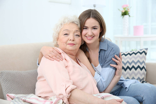 Beautiful girl with grandmother on couch at home - Photo, Image