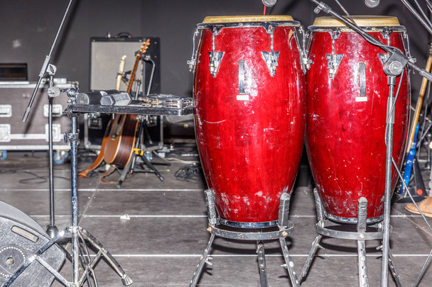Conjunto de tambores, guitarra e alto-falantes, em um palco
 - Foto, Imagem