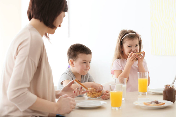 Mother and children having breakfast at home - Фото, зображення