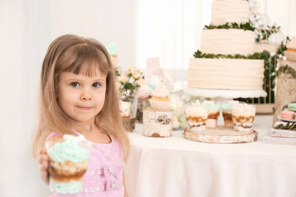 Cute girl with dessert near table served for party - Foto, Bild