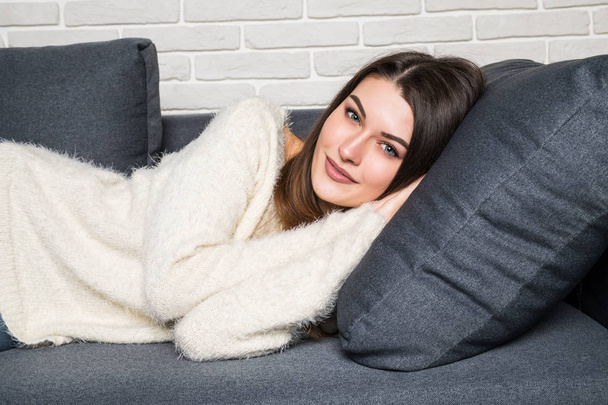 Mujer joven sonriente acostada en el sofá en casa
 - Foto, Imagen