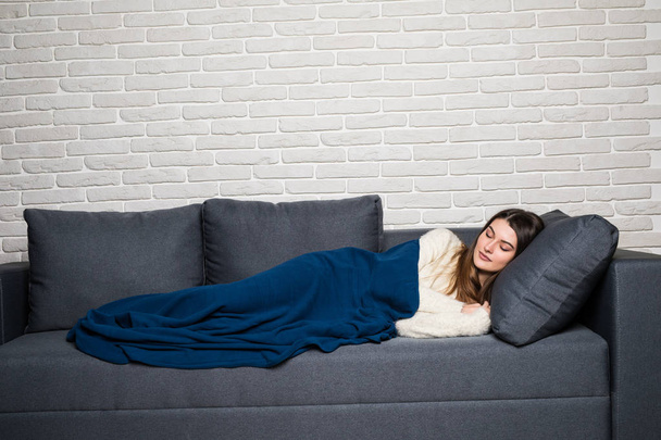 Hermosa joven mujer está durmiendo y viendo dulces sueños en el sofá en casa
 - Foto, imagen