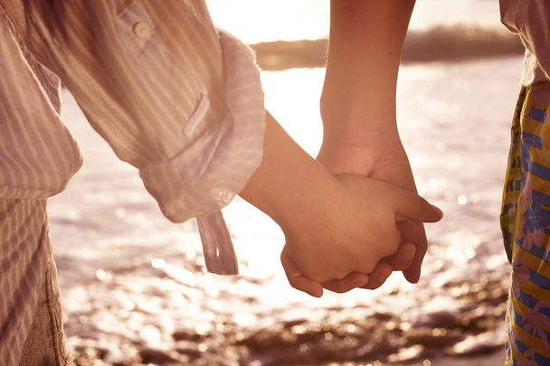 Молодая пара держится за руки на пляже
 - Фото, изображение