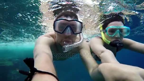 Mann und Frau halten sich unter Wasser an den Händen und blicken in die Kamera. - Filmmaterial, Video