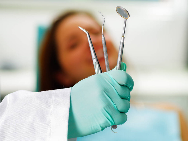 Belle patiente ayant un traitement dentaire au cabinet de dentistes pendant que le médecin tient ses instruments
 - Photo, image