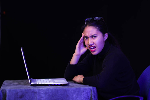 Beautiful girl got stressful in front of her laptop on dark background - Фото, зображення