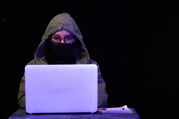 Portrait of hacker with laptop on dark background - Photo, Image