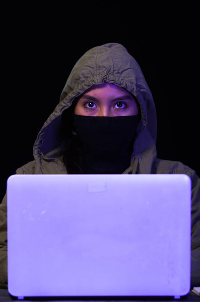 Portrait of hacker with laptop on dark background - Фото, изображение