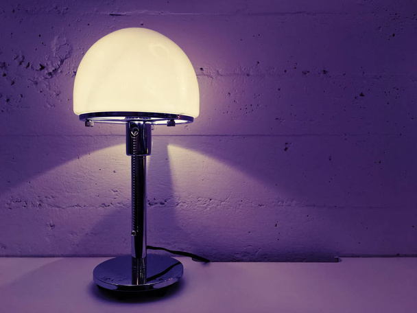 Lámpara de mesa de diseño moderno cerca de pared de hormigón
 - Foto, Imagen