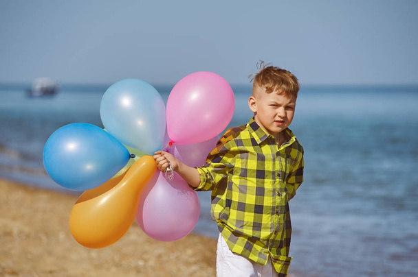 Gay αγόρι παίζει με μπαλόνια από τη θάλασσα. Η έννοια των καλοκαιρινών διακοπών - Φωτογραφία, εικόνα