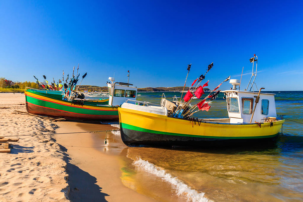 Яркие рыбацкие лодки на песчаном пляже Балтийского моря в Сопоте
 - Фото, изображение
