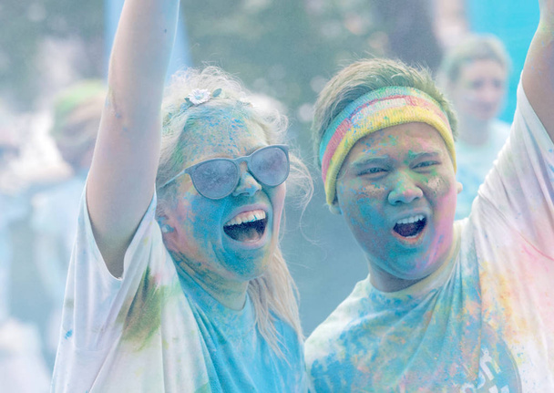 Teenagers covered with color dust rasing arms in the air - Photo, Image