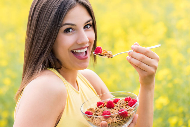 Cute girl eating healthy cereal breakfast outdoors. - Photo, Image
