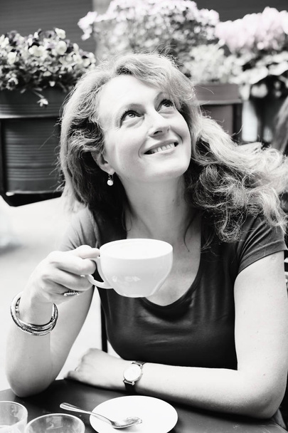 зрелая женщина сидит в кафе на открытом воздухе
 - Фото, изображение