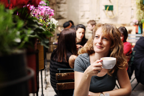 зрелая женщина сидит в кафе на открытом воздухе
 - Фото, изображение