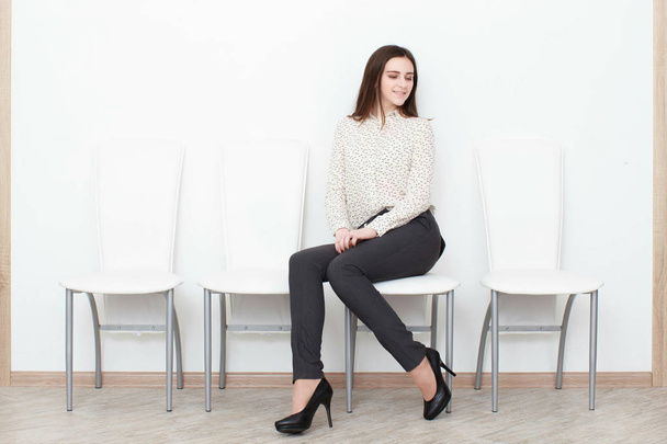 Chica atractiva sentada en una silla blanca moderna y relajarse en casa
 - Foto, imagen
