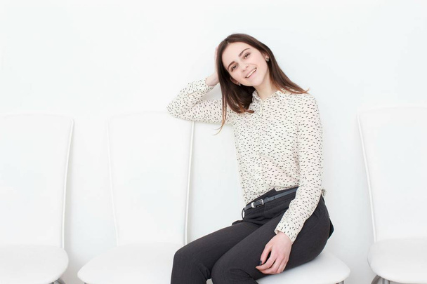 Vonzó lány ül a fehér modern szék és pihenni otthon - Fotó, kép