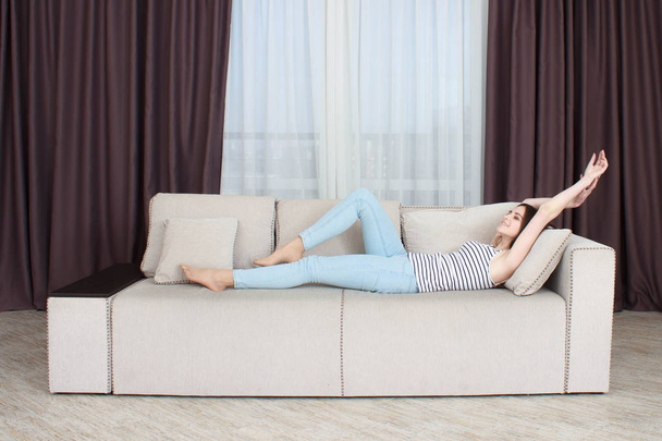 Beautiful woman lying on a white sofa In the interior of the apartments - Foto, Bild