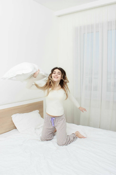 Woman in pajama smiling and throwing a pillow - Photo, Image