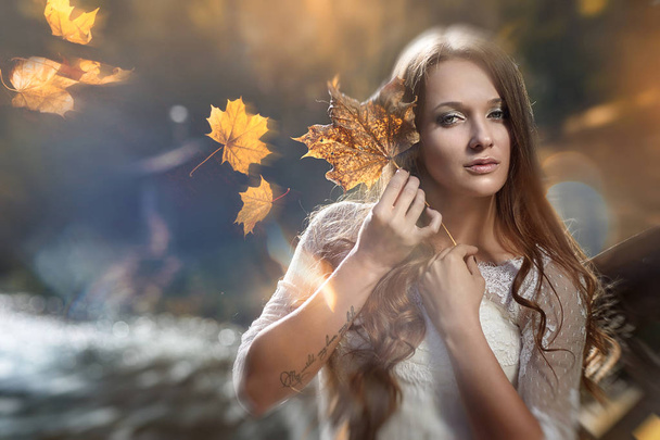 die Braut, ein Mädchen mit Herbstblättern in den Händen.  - Foto, Bild