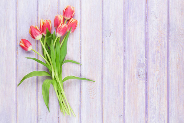 Rode tulpen over paarse tafel - Foto, afbeelding